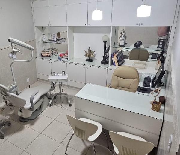 Consultório odontológico da IDB com cadeira, equipamentos e estante decorativa